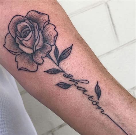 Small rose tattoo with name stem - Here’s a clever idea. Instead of working the name into the stem, you can get the name written across the stem. As we said earlier, red and black look fantastic together. Yari Instagram. An all-black stem with a bold font meets a romantic rose in this flower name tattoo. The artist has still made the overall tattoo look balanced.